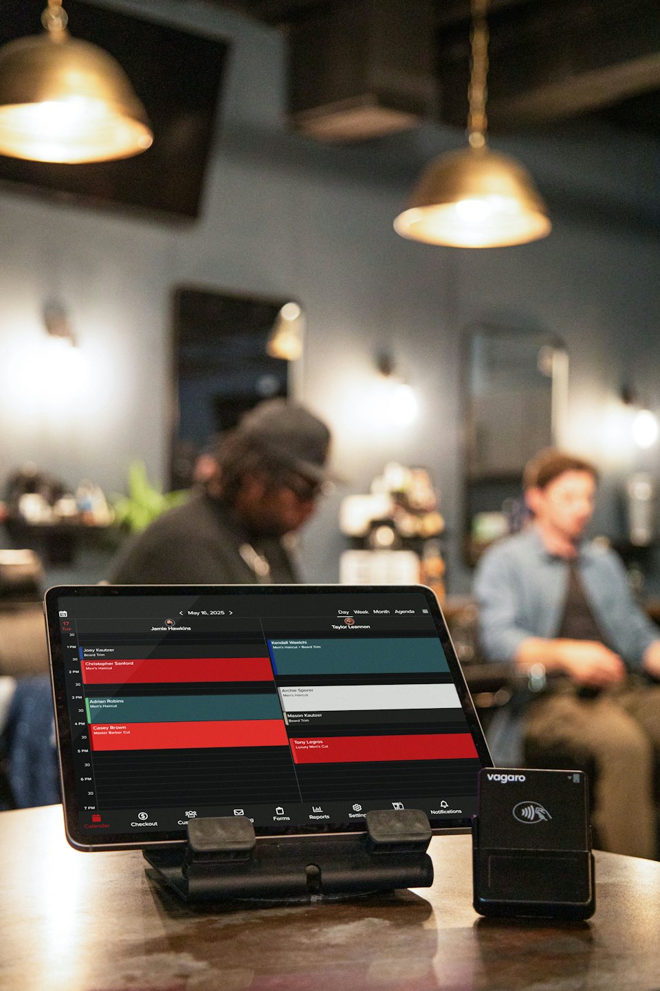 Ein digitales Tablet mit Friseurterminen liegt auf einer Holztheke.